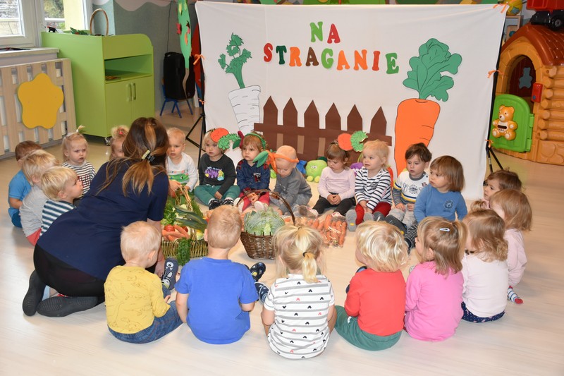 Dzieci i wychowawca na przedstawieniu Na Straganie