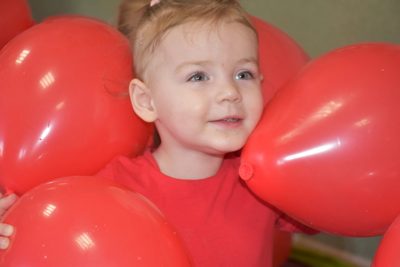 Dziewczynka otoczona czerwonymi balonami