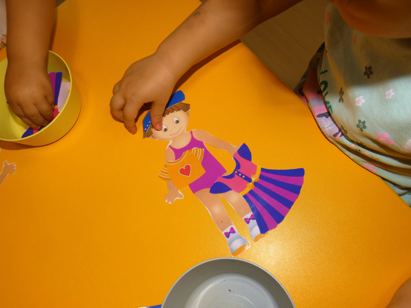 Dziecko układające lalkę z kartek